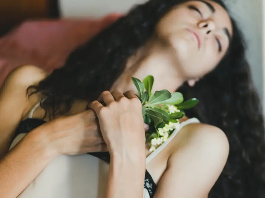 A serene woman holding fresh flowers close to her heart, symbolizing self-care, intimacy, and Gaia in Love’s commitment to empowering women through sexual wellness and self-discovery.