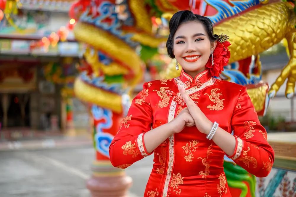 A cheerful woman in a red cheongsam celebrating Chinese New Year, representing Gaia in Love's innovative spirit and commitment to creating the best sex toys for women worldwide.