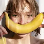 A joyful young woman holding a banana, symbolizing playfulness and empowerment through Gaia in Love's innovative female vibrators.