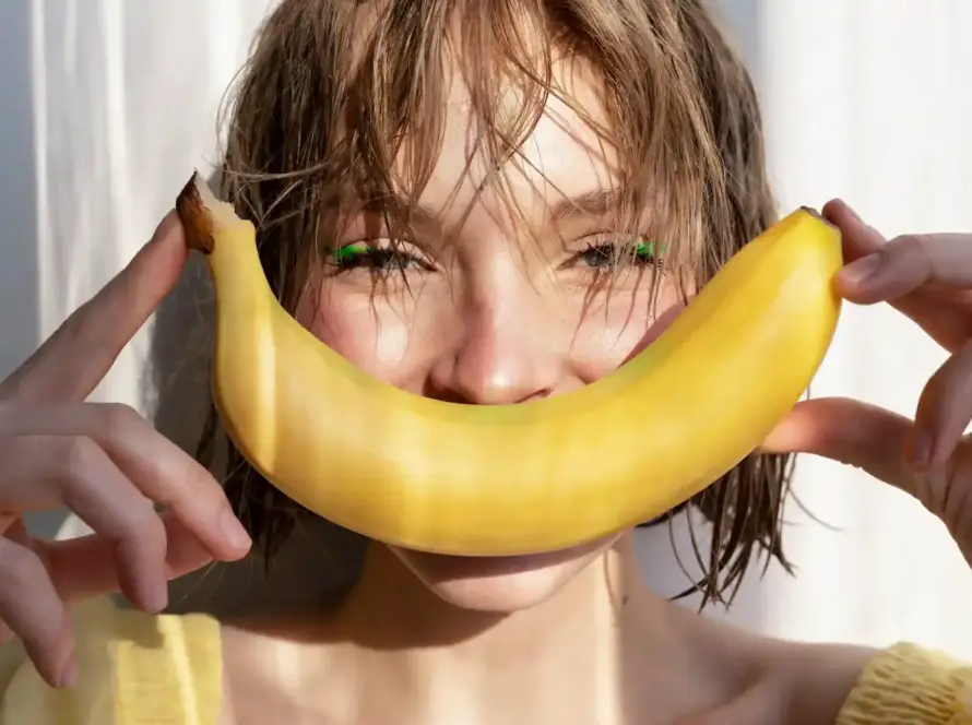 A joyful young woman holding a banana, symbolizing playfulness and empowerment through Gaia in Love's innovative female vibrators.