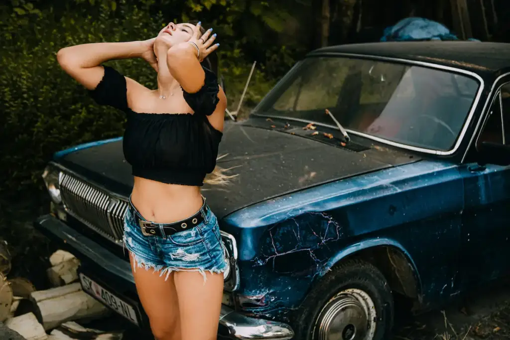 Confident woman posing in front of a vintage car, symbolizing empowerment and freedom, aligning with Gaia in Love’s brand values of embracing individuality.