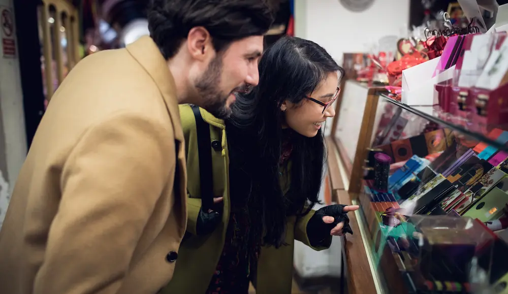 A couple browsing a variety of adult products in a store, reflecting Gaia in Love’s inclusive approach to sex tools for women.