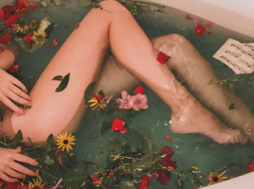 Elegant legs immersed in a floral bath, representing relaxation and self-care. Discover Gaia in Love’s premium sex equipment for women, designed for comfort and wellness.