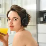 Sporty woman enjoying juice with headphones, reflecting health and lifestyle, incorporating magic wands wellness tools by Gaia in Love.