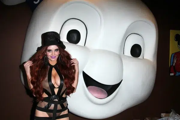 A model poses at the AVN Novelty Expo 2025, standing in front of a large figure, showcasing the fun and vibrant atmosphere of the event.