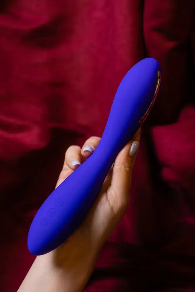 Hand holding a blue silicone vibrator, representing a product variant within a sex toy series.